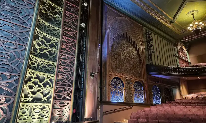 Salle de cinéma ancienne au décor mauresque, avec ses rangées de fauteuils rouges